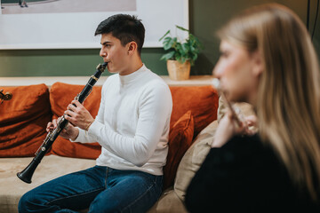 Two people are seen playing a clarinet and a flute together in a comfortable indoor setting, showcasing harmonious teamwork and passion for music. © qunica.com