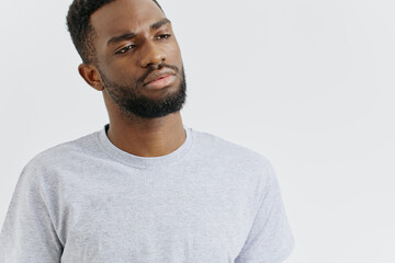 Fototapeta premium Confident young man in casual grey tshirt standing with hands on hips against a plain white background