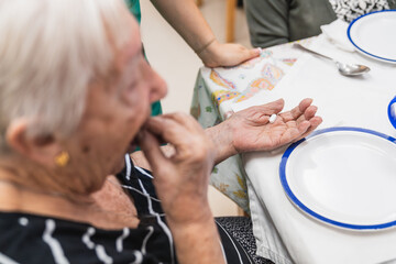 Elderly woman taking medication in nursing home