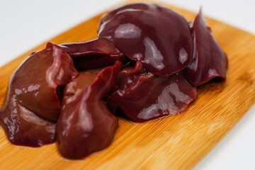 Close-up of raw chicken liver on a wooden board on a white background. The concept of healthy eating, cooking. High quality photo