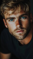 Obraz premium Portrait of a young man with blue eyes and thick eyebrows in a dark background, atmospheric and expressive look