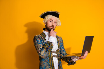 Modern interpretation of nobleman using laptop against bright yellow background, classic...