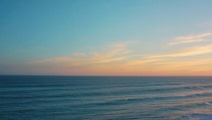 Fototapeta premium Ocean Sunset Horizon: A serene seascape captures the beauty of a pastel sunset as it paints the sky with hues of pink and orange, while the deep blue ocean stretches into the distance.