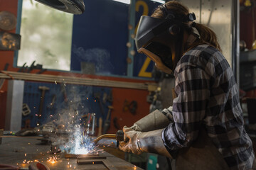 Sparks, glowing hot steel particles, getting on the camera while a woman welder welding metal....