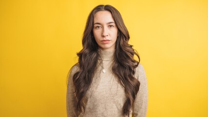 Confident woman standing against yellow background
