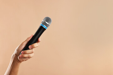 Man with microphone on beige background, closeup. Space for text