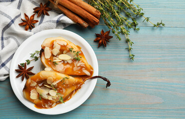 Delicious pears with caramel sauce, almond flakes and spices on blue wooden table, flat lay