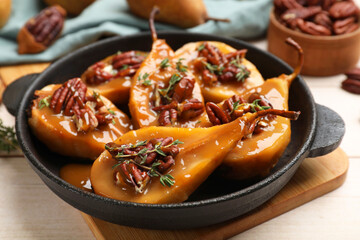 Delicious pears with caramel sauce, pecan nuts and thyme on wooden table, closeup
