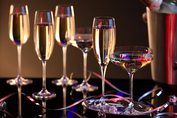 Champagne in glasses and party streamers on black mirror surface