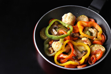 Frying pan with vegetables and mushrooms on stove, closeup
