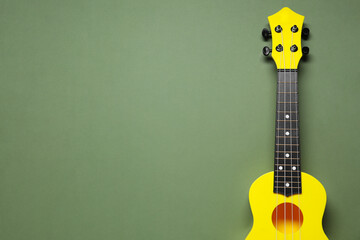 Naklejka premium One ukulele on olive background, top view. Space for text