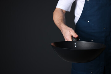 Chef with frying pan on black background, closeup. Space for text