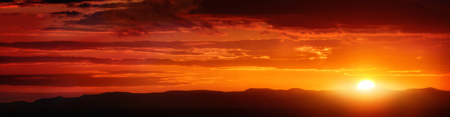 Wide panorama of a glowing orange striped sunset sky
