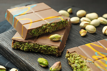 Pieces of Dubai chocolate bars with pistachios and knafeh on black table, closeup
