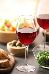 Red wine and delicious dinner served on grey table, closeup