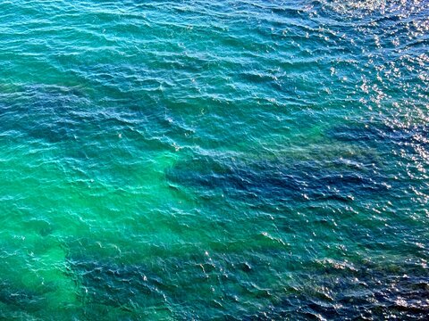 Amazing sea watercolor blue emerald green surface with sun reflections.