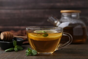Tasty mint tea in cup, lemon and fresh leaves on wooden table, closeup