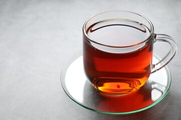 Refreshing black tea in cup on grey table, closeup. Space for text