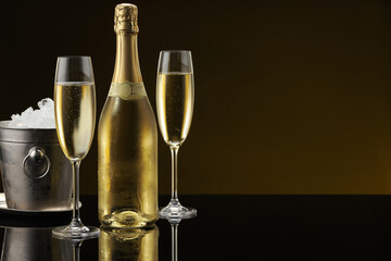 Bottle of sparkling wine, glasses and cooler bucket on black mirror surface. Space for text