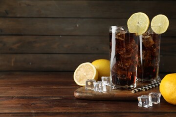 Fresh iced cola with lemon slices on wooden table. Space for text