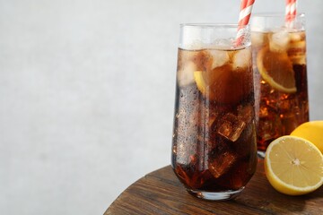 Refreshing iced cola with lemon slices on wooden table, closeup. Space for text
