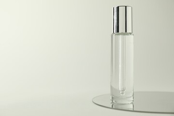 Bottle of serum and mirror on light background, space for text
