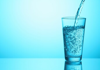 Pouring soda water into glass on light blue background, closeup. Space for text