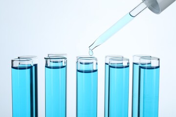 Dripping liquid into test tubes on white background