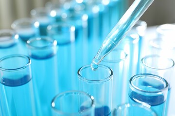 Dripping liquid into test tubes on light background, closeup