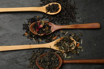 Different types of tea brew on black table, flat lay