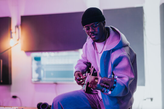 Young musician playing guitar in a modern music studio setting