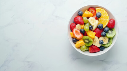 A refreshing summer fruit salad served in a bowl on a white marble surface.