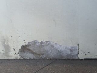 A weathered white wall with peeling paint, exposing the rough concrete underneath. The cracked and worn texture adds a rustic and aged aesthetic