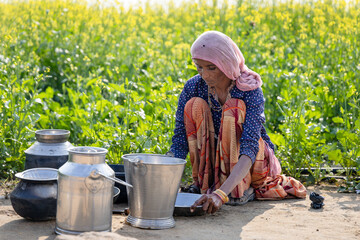 poor malnutrition village women living below poverty line washing dishes with mustard fields behind