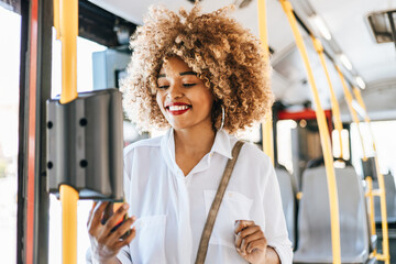 Beautiful black woman using ticket machine and paying contactless for bus or tram. Modern city...
