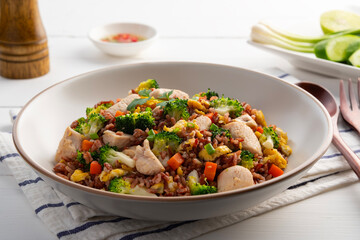 Healthy asian food.Thai fried Organic Red Brown Jasmine Rice (unpolished rice) with chicken breast and broccoli carrot egg in white plate.clean food.