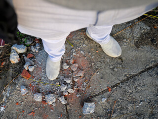 Obraz premium Man wearing white pants and light-colored shoes stands on a rough.