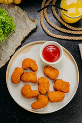 Crispy chicken nuggets with ketchup on plate with fresh ingredients in stylish food presentation