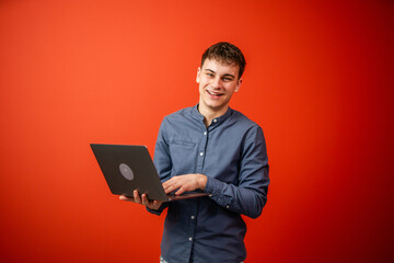 young businessman with laptop stand in front red background studio shot
