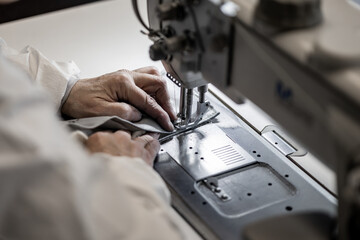 A skilled worker carefully sews industrial fabric using a heavy-duty sewing machine. The close-up highlights precision, craftsmanship, and expertise in textile manufacturing and upholstery work