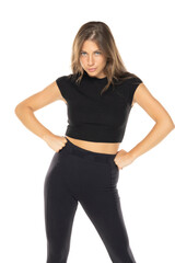 Fototapeta premium Woman in black crop top and leggings, hands on hips, intense gaze, standing confidently on white background