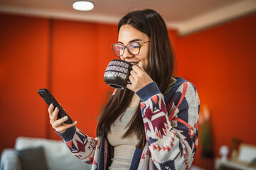 young woman use mobile phone and drink coffee at home