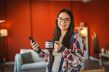 portrait of young woman use mobile phone and drink coffee at home
