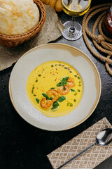 Creamy shrimp soup with spinach, garnished with chili flakes and herb oil, served in a gourmet style