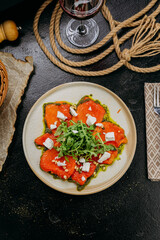 Roasted bell pepper carpaccio with arugula, feta cheese, pine nuts, and pesto, in gourmet style