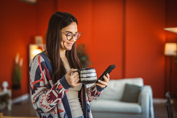 young woman use mobile phone and drink coffee at home