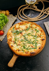 Gourmet four-cheese pizza with arugula, served on a wooden board in a stylish restaurant setting
