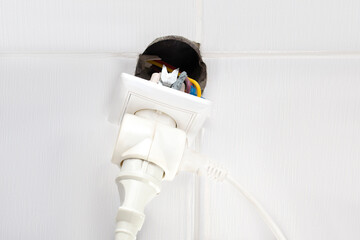 Socket stick out of wall with cables,connected devices.load on power grid,electric danger.Installation of new electrical switch socket in bathroom for house safety