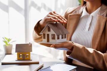 Hand of woman holding model house, real estate mortgage insurance and mortgage loan property...