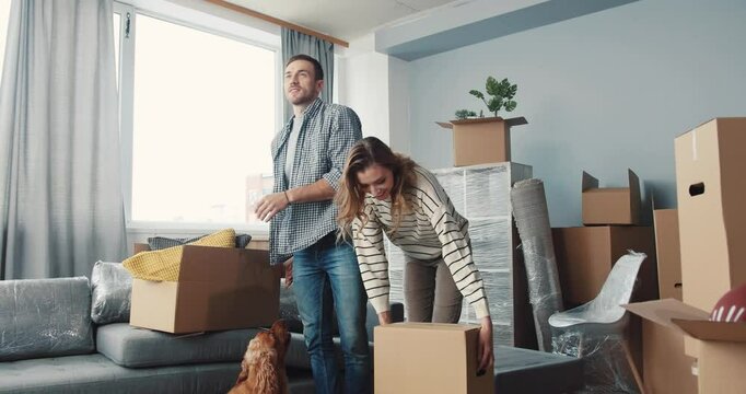 A couple joyfully unpacking their boxes in the cozy living room of their new home together